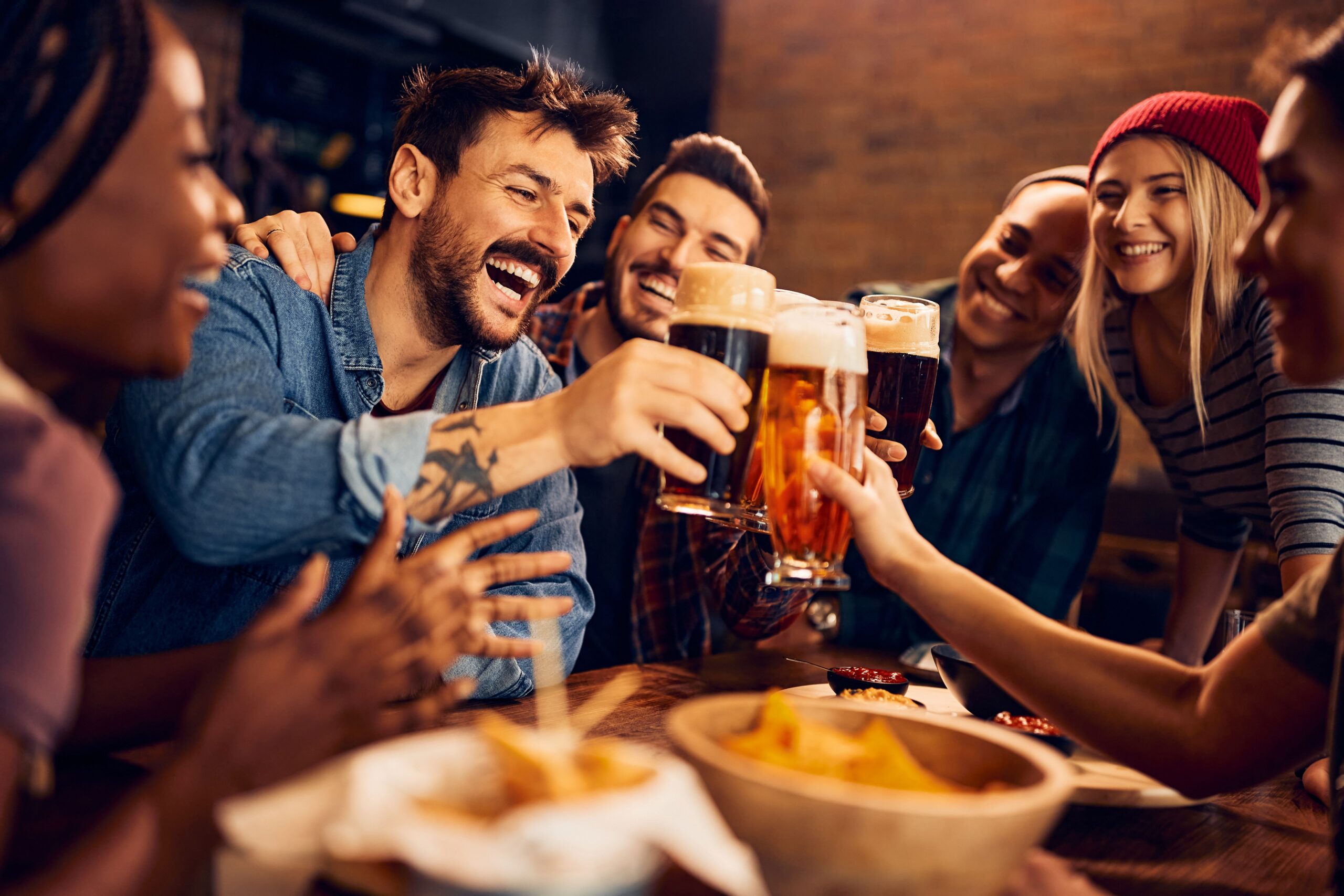 Friends clinking beer glasses at a bar