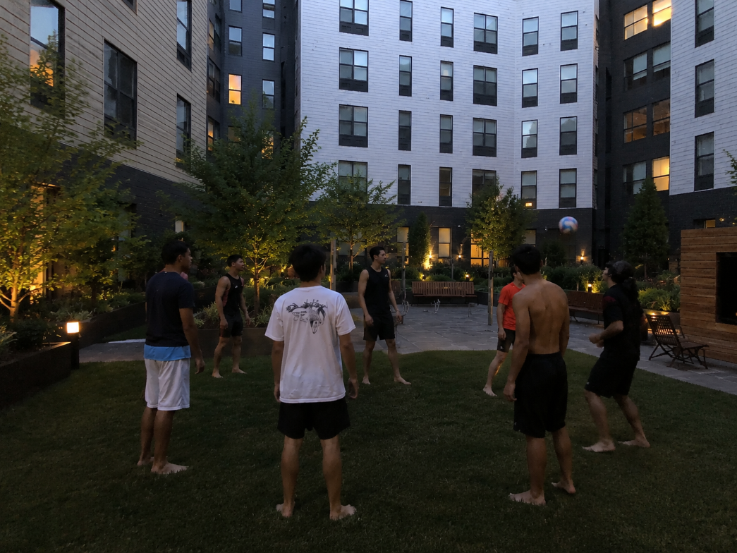 Friends playing volleyball in the courtyard at dusk