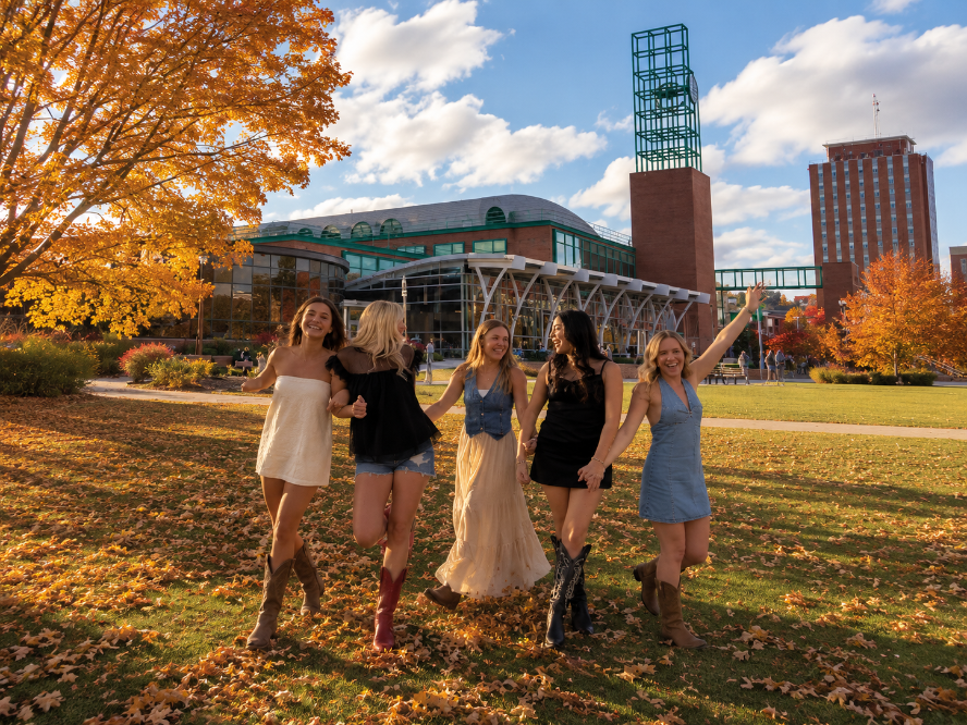 Five friends walking on campus in the fall